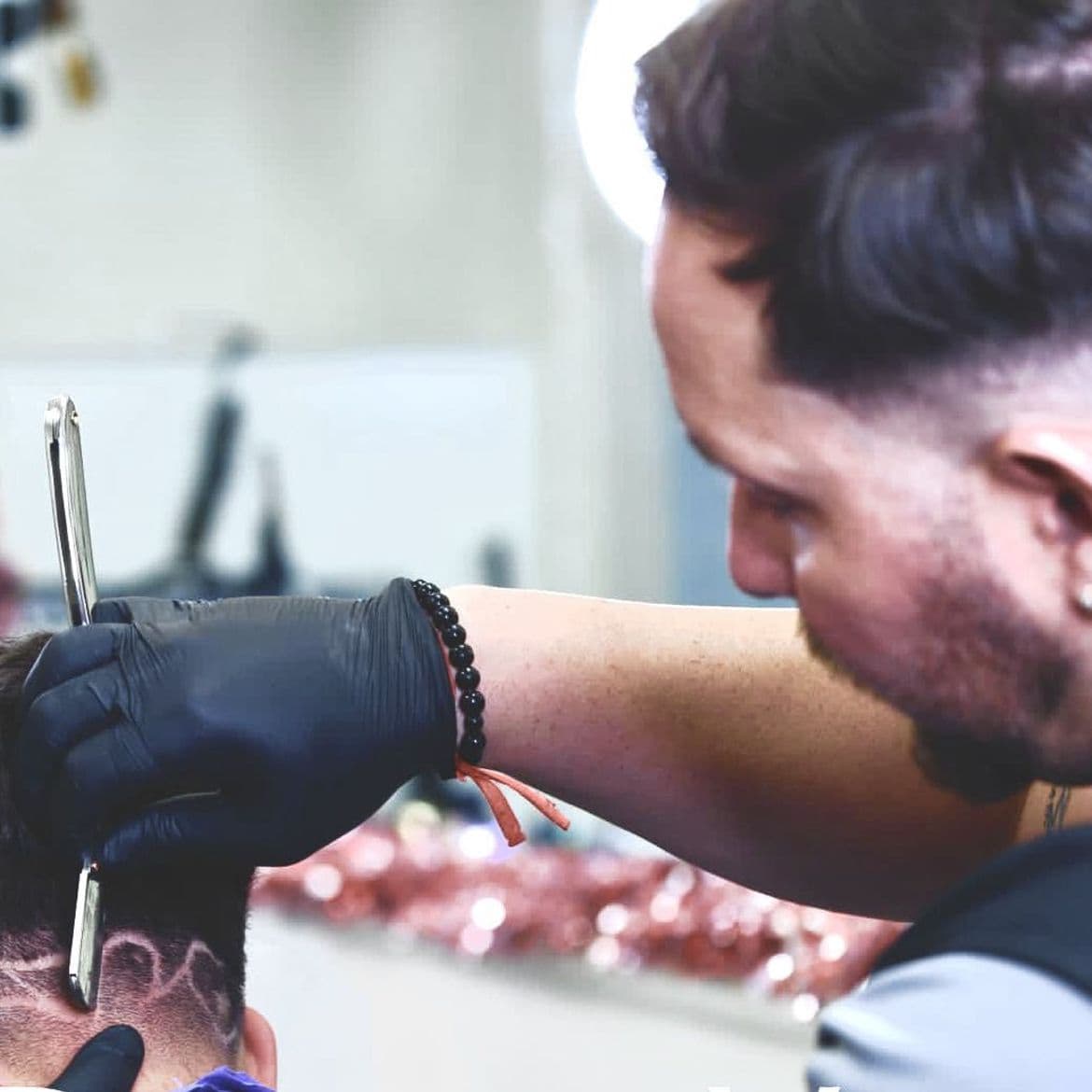 Barber using a straight razor to finish a design at Tu Barber Cubanito in Brighton